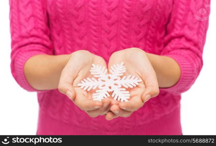 christmas, holidays and people concept - close up of woman in pink sweater holding snowflake