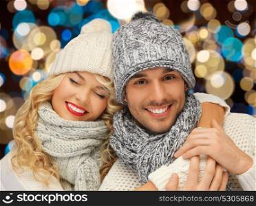 christmas, holidays and people concept - happy couple in winter hats over lights background. happy couple in hats over lights background