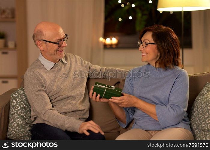 christmas, holidays and people concept - happy senior couple with gift box at home. happy senior couple with gift box at home