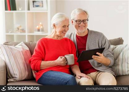 christmas, holidays and people concept - happy senior couple with tablet pc computer at home. happy senior couple with tablet pc at christmas