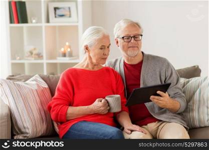 christmas, holidays and people concept - happy senior couple with tablet pc computer at home. happy senior couple with tablet pc at christmas