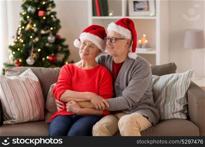christmas, holidays and people concept - happy smiling senior couple in santa hats at home. happy senior couple in santa hats at christmas