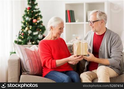 christmas, holidays and people concept - happy smiling senior couple with gift box at home. happy smiling senior couple with christmas gift