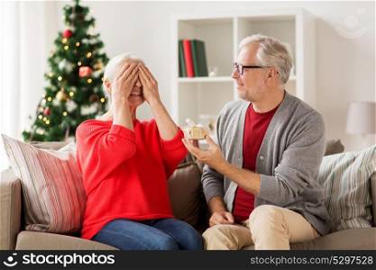 christmas, holidays and people concept - happy smiling senior couple with gift box at home. happy smiling senior couple with christmas gift