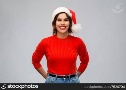 christmas, holidays and people concept - happy smiling young woman in santa helper hat over grey background. happy young woman in santa hat on christmas