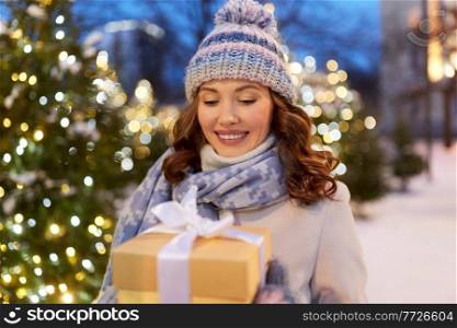 christmas, holidays and people concept - happy smiling young woman with gift box in winter park. happy young woman with christmas gift in winter