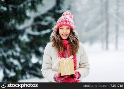 christmas, holidays and people concept - happy teenage girl or young woman with gift box outdoors winter park. happy young woman with christmas gift in winter