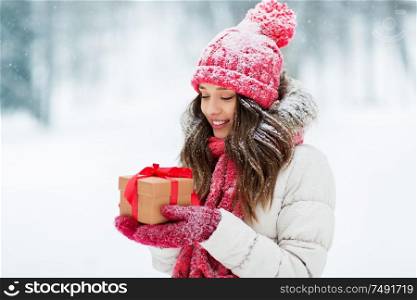 christmas, holidays and people concept - happy teenage girl or young woman with gift box outdoors winter park. happy young woman with christmas gift in winter