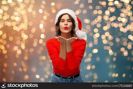 christmas, holidays and people concept - happy young woman in santa helper hat sending air kiss over grey background. happy young woman in santa hat sending air kiss
