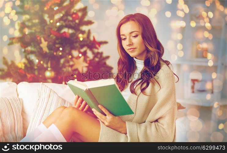 christmas, holidays and people concept - happy young woman reading book at home. happy woman reading book at home for christmas