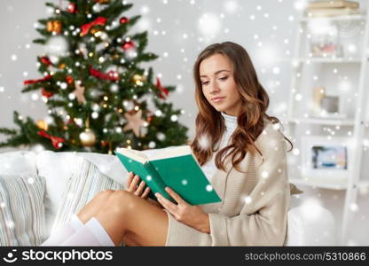 christmas, holidays and people concept - happy young woman reading book at home over snow. happy woman reading book at home for christmas