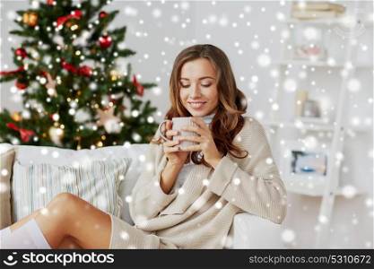 christmas, holidays and people concept - happy young woman with cup of coffee or tea at home over snow. happy woman with cup of tea at home for christmas