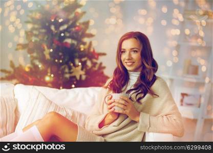 christmas, holidays and people concept - happy young woman with cup of coffee or tea at home. happy woman with cup of tea at home for christmas