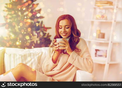 christmas, holidays and people concept - happy young woman with cup of coffee or tea at home. happy woman with cup of tea at home for christmas