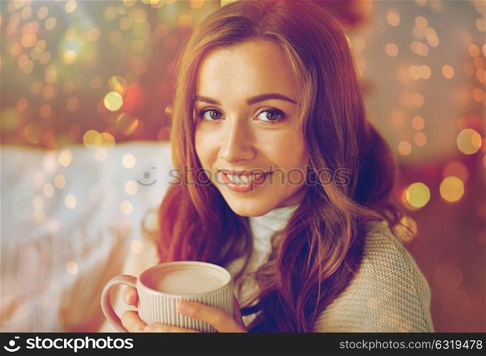 christmas, holidays and people concept - happy young woman with cup of coffee or cocoa drink at home. happy woman drinking cocoa at home for christmas