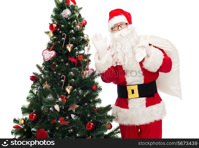 christmas, holidays and people concept - man in costume of santa claus with bag and christmas tree waving hand