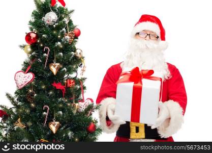 christmas, holidays and people concept - man in costume of santa claus with gift box and tree