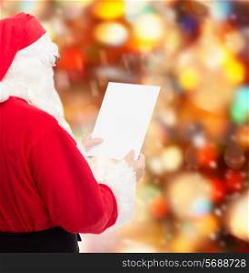 christmas, holidays and people concept - man in costume of santa claus reading letter over red lights background