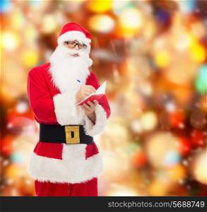 christmas, holidays and people concept - man in costume of santa claus with notepad and pen over red lights background