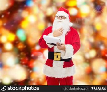 christmas, holidays and people concept - man in costume of santa claus with notepad over red lights background