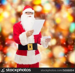 christmas, holidays and people concept - man in costume of santa claus reading letter over red lights background