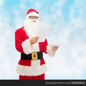 christmas, holidays and people concept - man in costume of santa claus reading letter over blue lights background