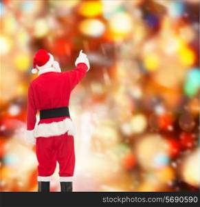 christmas, holidays and people concept - man in costume of santa claus pointing finger from back over red lights background