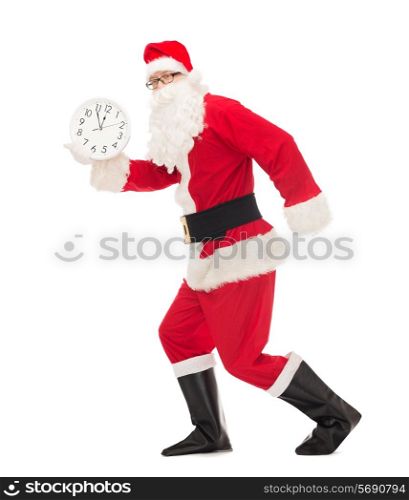 christmas, holidays and people concept - man in costume of santa claus running with clock showing twelve