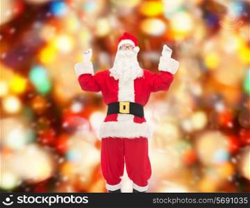 christmas, holidays and people concept - man in costume of santa claus having fun over red lights background