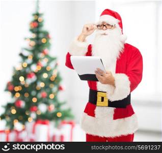 christmas, holidays and people concept - man in costume of santa claus with notepad over living room with tree background