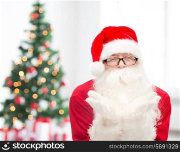 christmas, holidays and people concept - man in costume of santa claus blowing on palms over living room with tree
