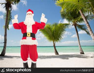 christmas, holidays and people concept - man in costume of santa claus having fun over tropical beach background