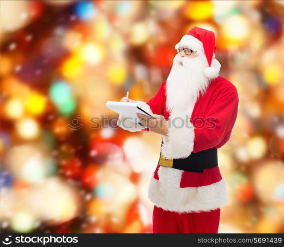christmas, holidays and people concept - man in costume of santa claus with notepad and pen over red lights background