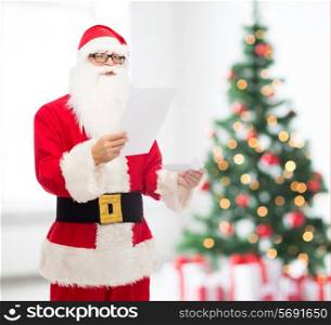 christmas, holidays and people concept - man in costume of santa claus reading letter over living room with tree background