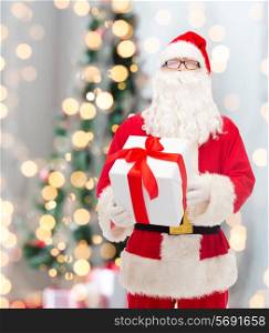 christmas, holidays and people concept - man in costume of santa claus with gift box over tree lights background