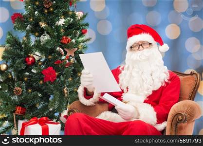 christmas, holidays and people concept - man in costume of santa claus with letter over blue lights background