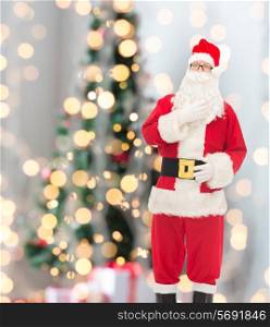 christmas, holidays and people concept - man in costume of santa claus over lights background over tree lights background