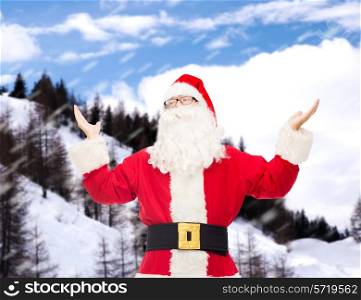 christmas, holidays and people concept - man in costume of santa claus with raised hands over snowy mountains background