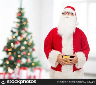 christmas, holidays and people concept - man in costume of santa claus over living room with tree background