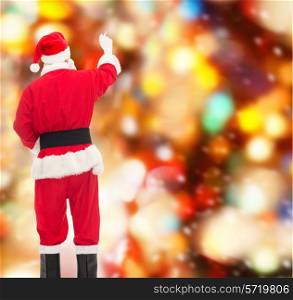 christmas, holidays and people concept - man in costume of santa claus writing something from back over red lights background