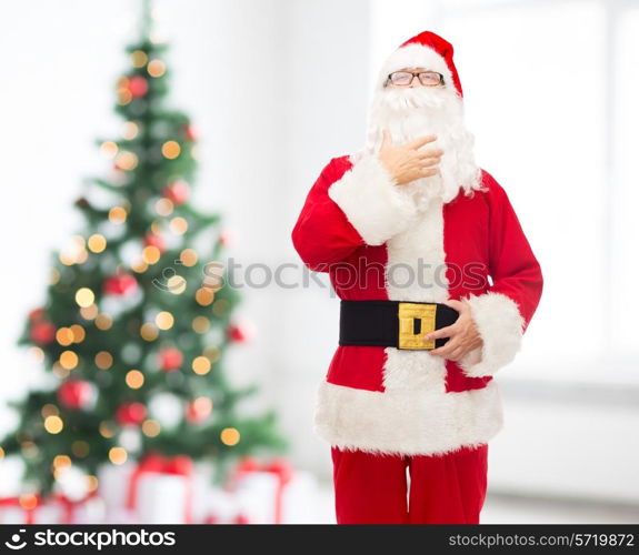 christmas, holidays and people concept - man in costume of santa claus over living room and tree background