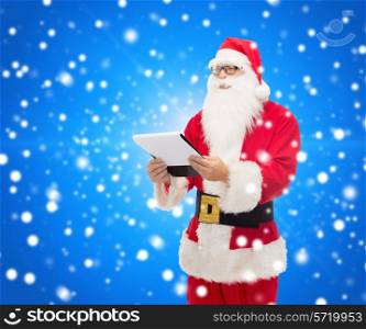 christmas, holidays and people concept - man in costume of santa claus with notepad over blue snowy background