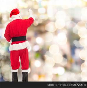christmas, holidays and people concept - man in costume of santa claus writing something from back over lights background