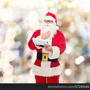 christmas, holidays and people concept - man in costume of santa claus with notepad over lights background