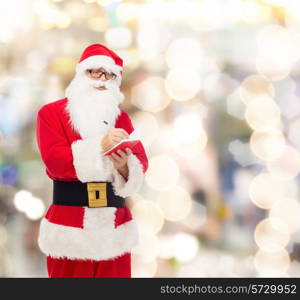 christmas, holidays and people concept - man in costume of santa claus with notepad and pen over lights background