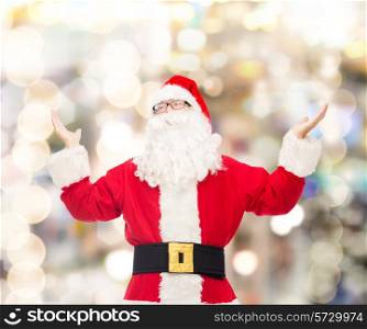 christmas, holidays and people concept - man in costume of santa claus with raised hands over lights background