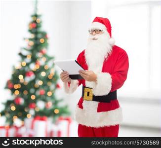 christmas, holidays and people concept - man in costume of santa claus with notepad over living room and tree background