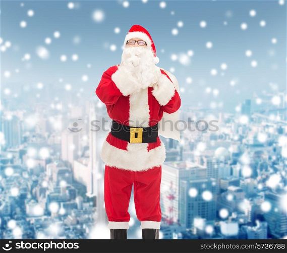 christmas, holidays and people concept - man in costume of santa claus with bag making hush gesture over snowy city background