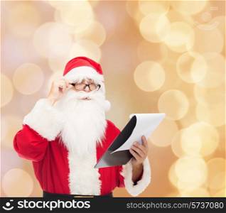 christmas, holidays and people concept - man in costume of santa claus with notepad over beige lights background