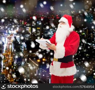 christmas, holidays and people concept - man in costume of santa claus with notepad and pen over snowy night city background